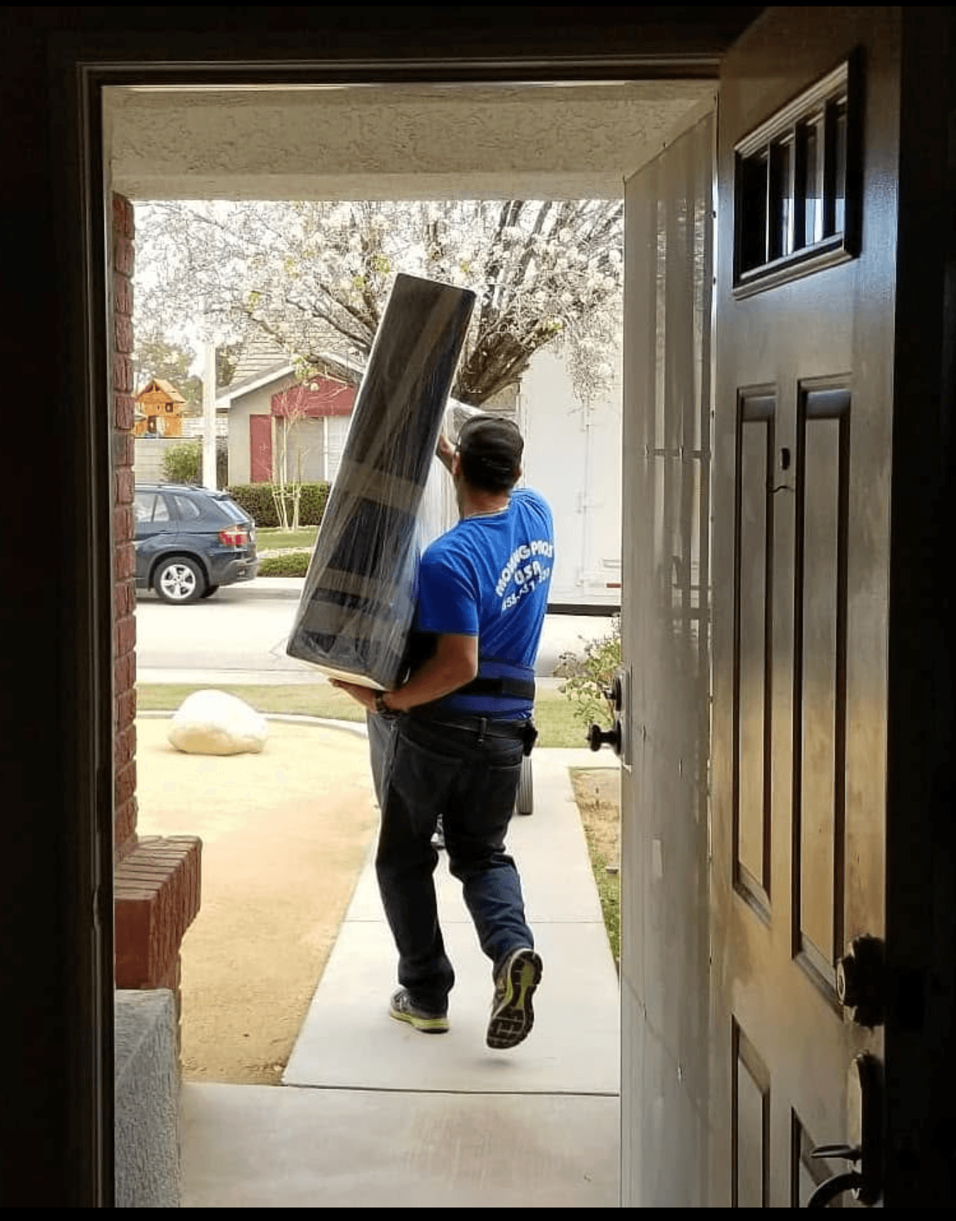 Moving Pro Inc mover carrying wrapped furniture out of a home